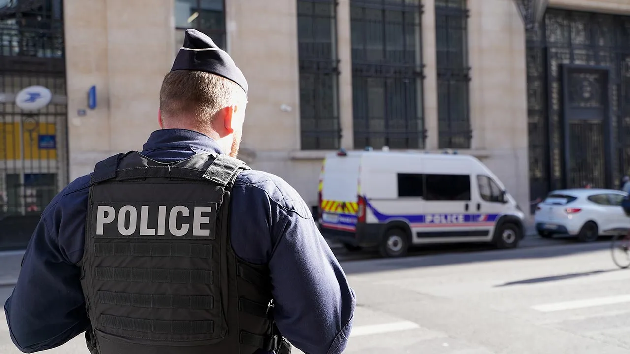 Police stand outside the Bank of America building in Paris, Saturday, March 28, 2026. (AP Photo/Nicolas Garriga)