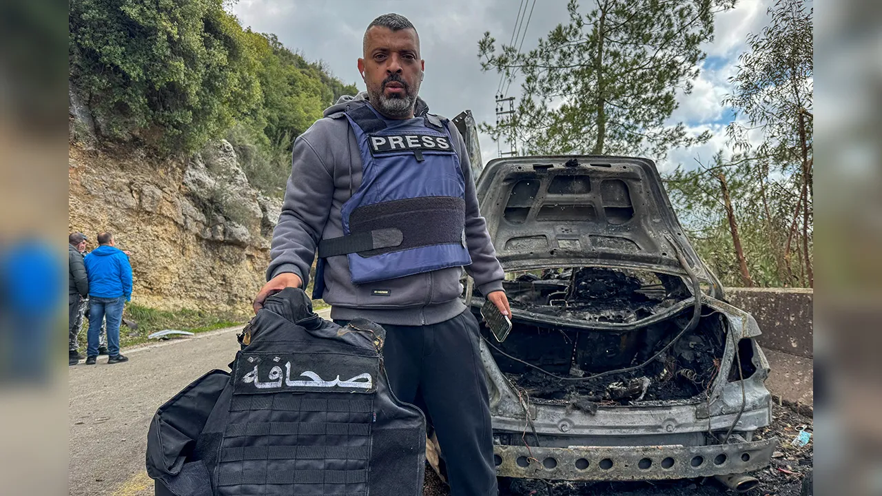 Al Mayadeen journalist Jamal Al-Gharabi holds a press vest next to a car destroyed by a targeted Israeli strike that killed Lebanese journalists Al Mayadeen reporter Fatima Ftouni and cameraman Mohammed Ftouni, and Al Manar reporter Ali Shaib, amid escalating hostilities between Israel and Hezbollah, as the U.S.-Israeli conflict with Iran continues, in Jezzine, in southern Lebanon, March 28, 2026. The sign on the vest reads "Press". Picture taken with a mobile phone. REUTERS/Ali Hankir
