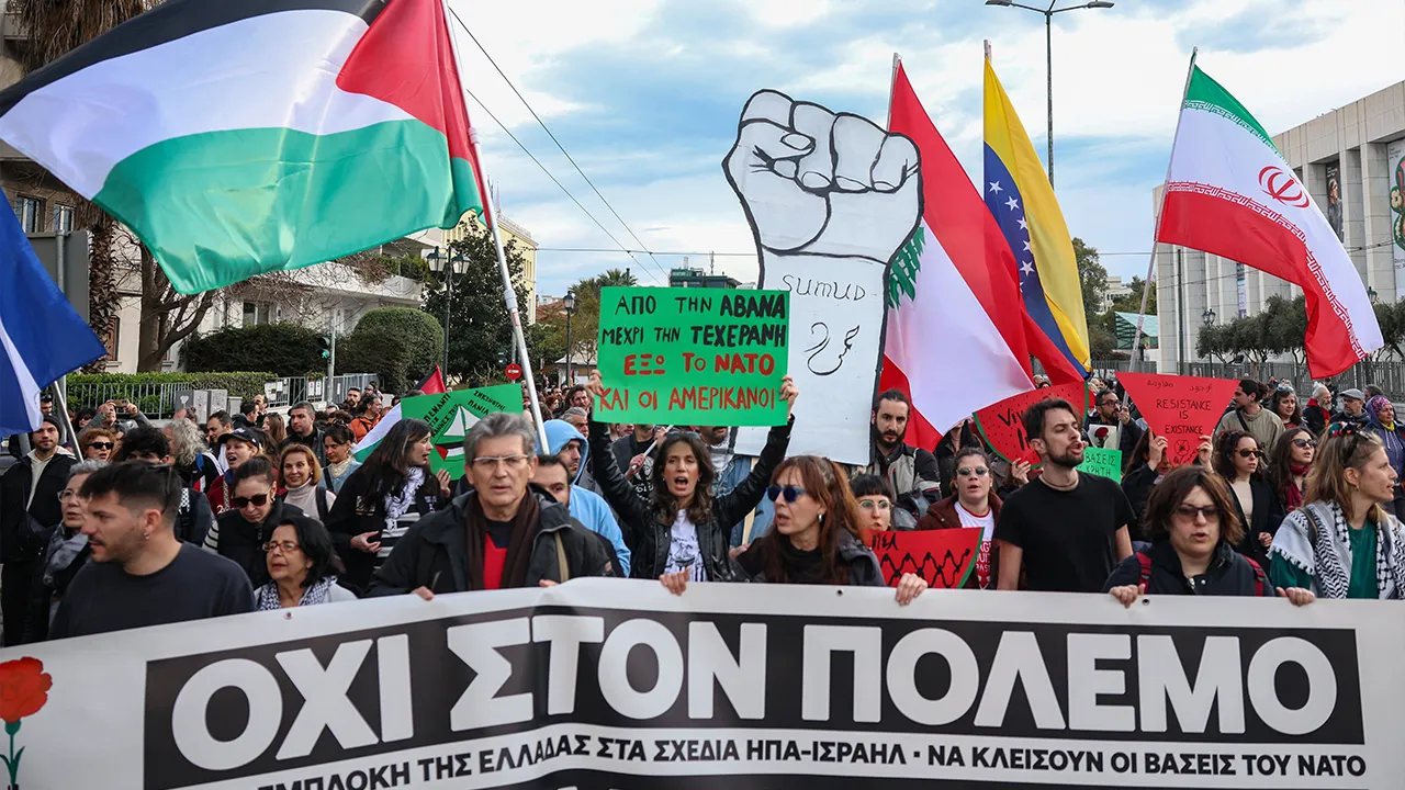 Protesters hold flags and march behind a banner reading "No to war", during an anti-war protest in conjunction with the "No Kings" protests in the United States, in front of the US embassy in Athens, Greece, March 28, 2026. REUTERS/Louisa Gouliamaki