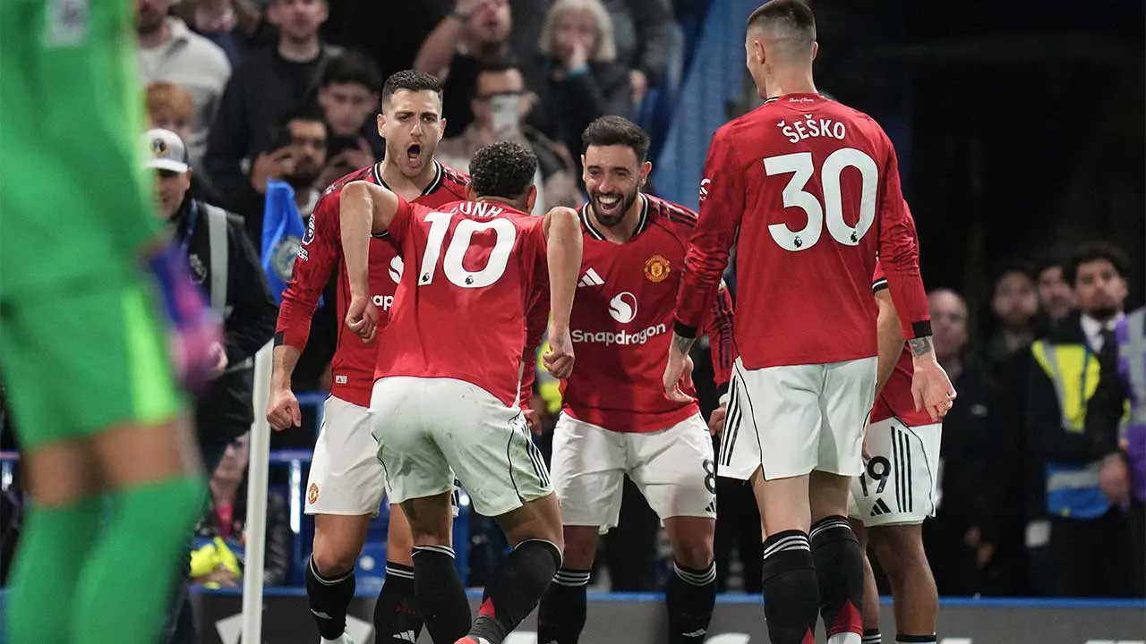 Manchester United's Matheus Cunha celebrates with teammates after scoring the opening goal during the English Premier League soccer match between Chelsea and Manchester United in London, Saturday, April 18, 2026. (AP Photo/Kirsty Wigglesworth)