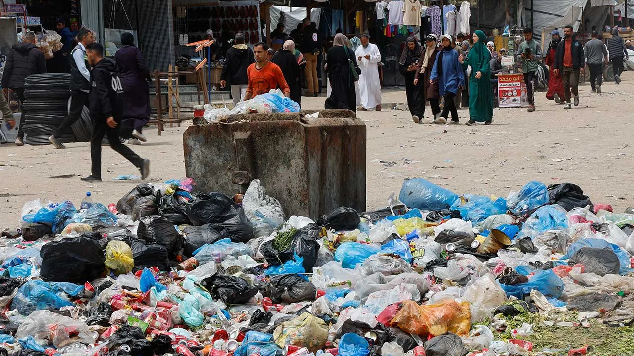 Palestinians walk past piles of garbage and waste near tents for displaced people, amid the spread of rodents, in Khan Younis in the southern Gaza Strip, April 27, 2026. REUTERS/Haseeb Alwazeer