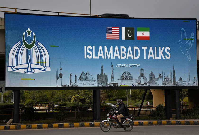 A man rides his motorbike past a billboard installed alongside a road as Pakistan prepares to host the U.S. and Iran for peace talks, in Islamabad, Pakistan, April 10, 2026. REUTERS/Waseem Khan 