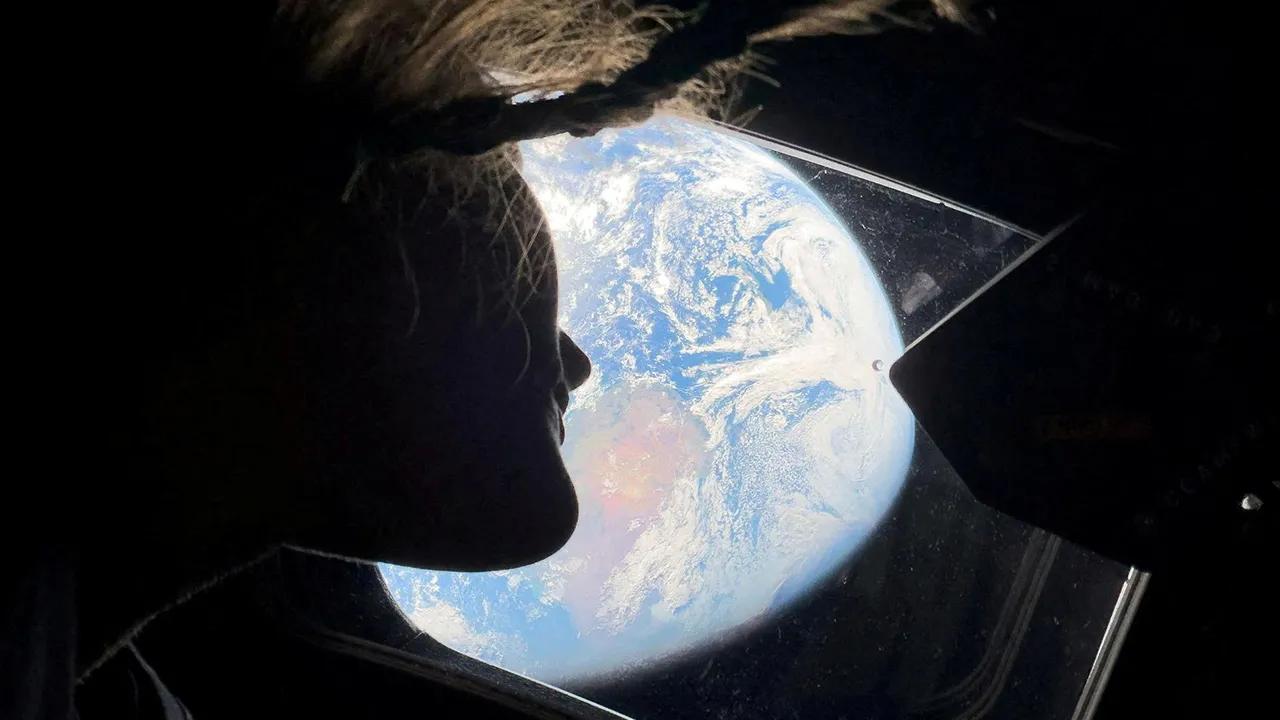 NASA astronaut and Artemis II mission specialist Christina Koch peers out of one of the Orion spacecraft's main cabin windows, looking back at Earth, as the crew travels towards the Moon April 2, 2026. NASA/Handout via REUTERS