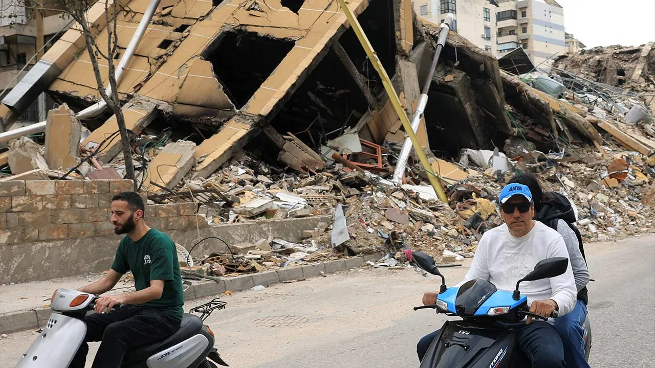 Displaced people ride past a destroyed building as they make their way while returning to the southern suburbs of Beirut, after a 10-day ceasefire between Lebanon and Israel went into effect, Lebanon, April 17, 2026. REUTERS/Adnan Abidi