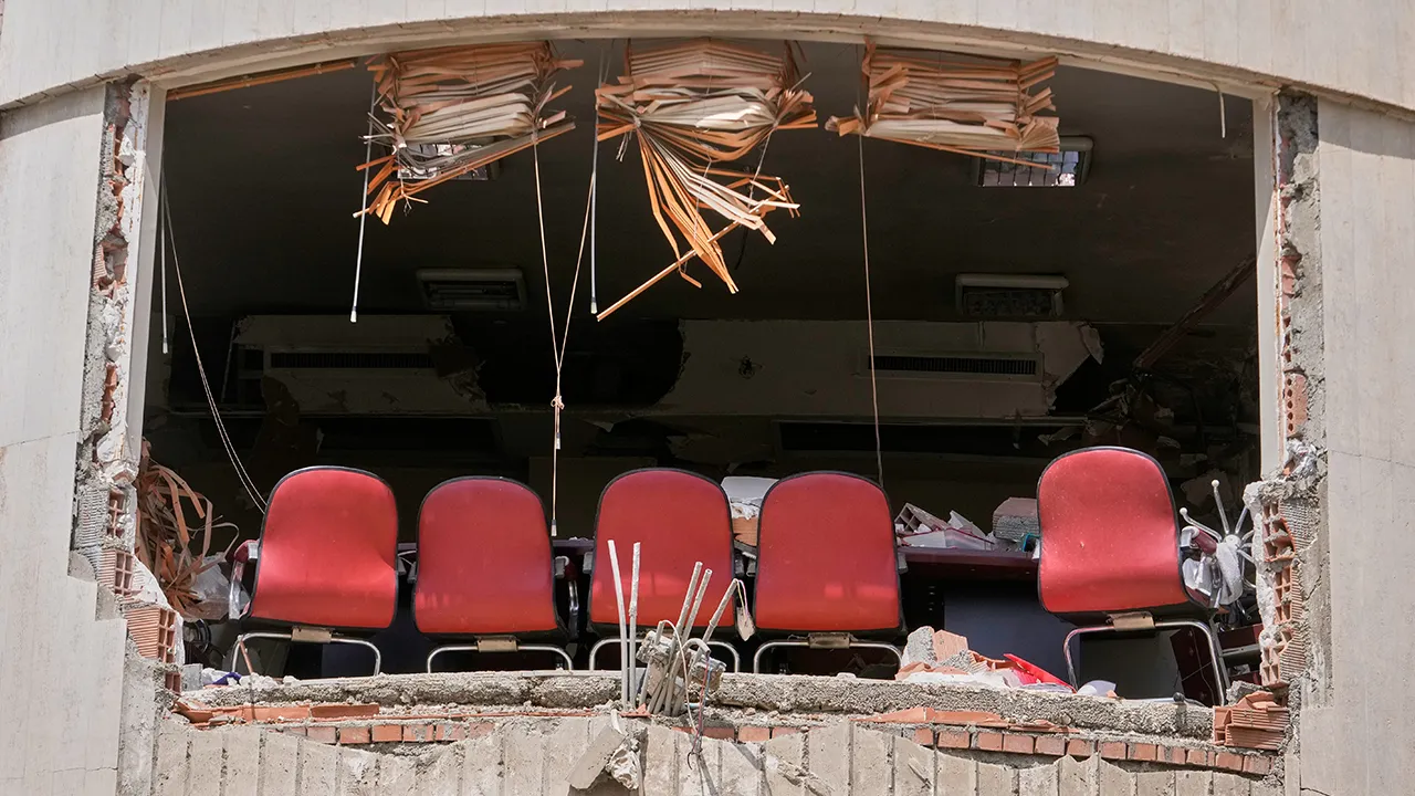 A row of chairs is seen through a hole left by U.S.-Israeli airstrikes Friday at Shahid Beheshti University in Tehran, Iran, Saturday, April 4, 2026. (AP Photo/Vahid Salemi)