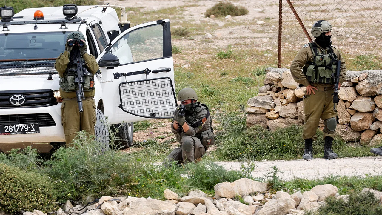 An Israeli soldier aims his weapon as heavy machinery demolishes Palestinian factories near Hebron in the Israeli-occupied West Bank, April 15, 2026. REUTERS/Yosri Aljamal