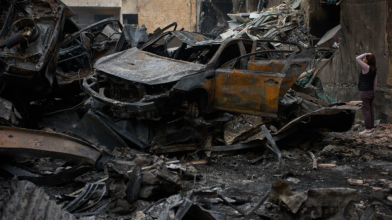 A resident checks damage to buildings as she walks near charred cars, at the site of Wednesday's Israeli airstrike, in Beirut, Lebanon, Friday, April 10, 2026. (AP Photo/Emilio Morenatti)