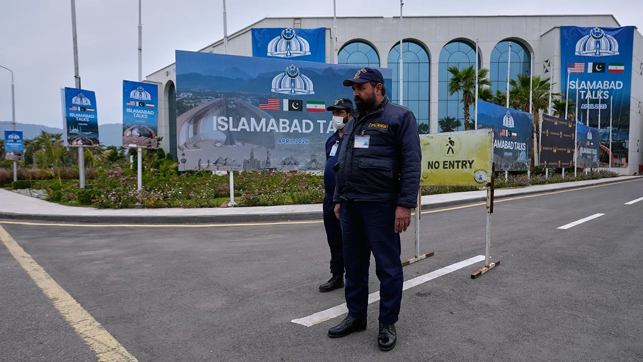 Security personnel stand next to signs regarding U.S. and Iran negotiations, outside a media facilitation center in Islamabad, Pakistan, Saturday, April 11, 2026. (AP Photo/Anjum Naveed)