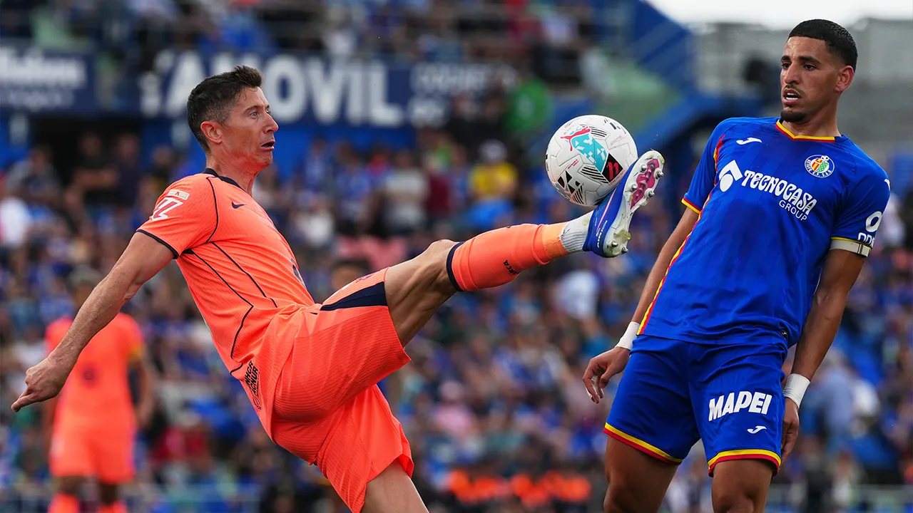 Barcelona's Robert Lewandowski, left, controls the ball past Getafe's Abdel Abqar during the Spanish La Liga soccer match between Getafe and Barcelona in Getafe, Spain, Saturday, April 25, 2026. (AP Photo/Manu Fernandez)