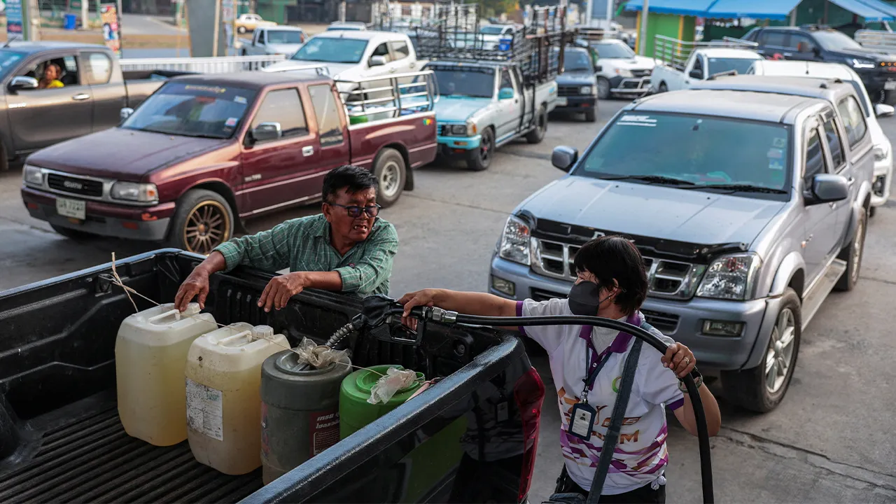 A worker fills plastic jerrycans with fuel as drivers queue in traffic at a fuel station, before Thailand's diesel price freeze expires on Monday, amid concerns about rising fuel prices linked to the U.S.-Israel conflict with Iran, in Nakhon Pathom province on the outskirts of Bangkok, Thailand, March 16, 2026. REUTERS/Chalinee Thirasupa