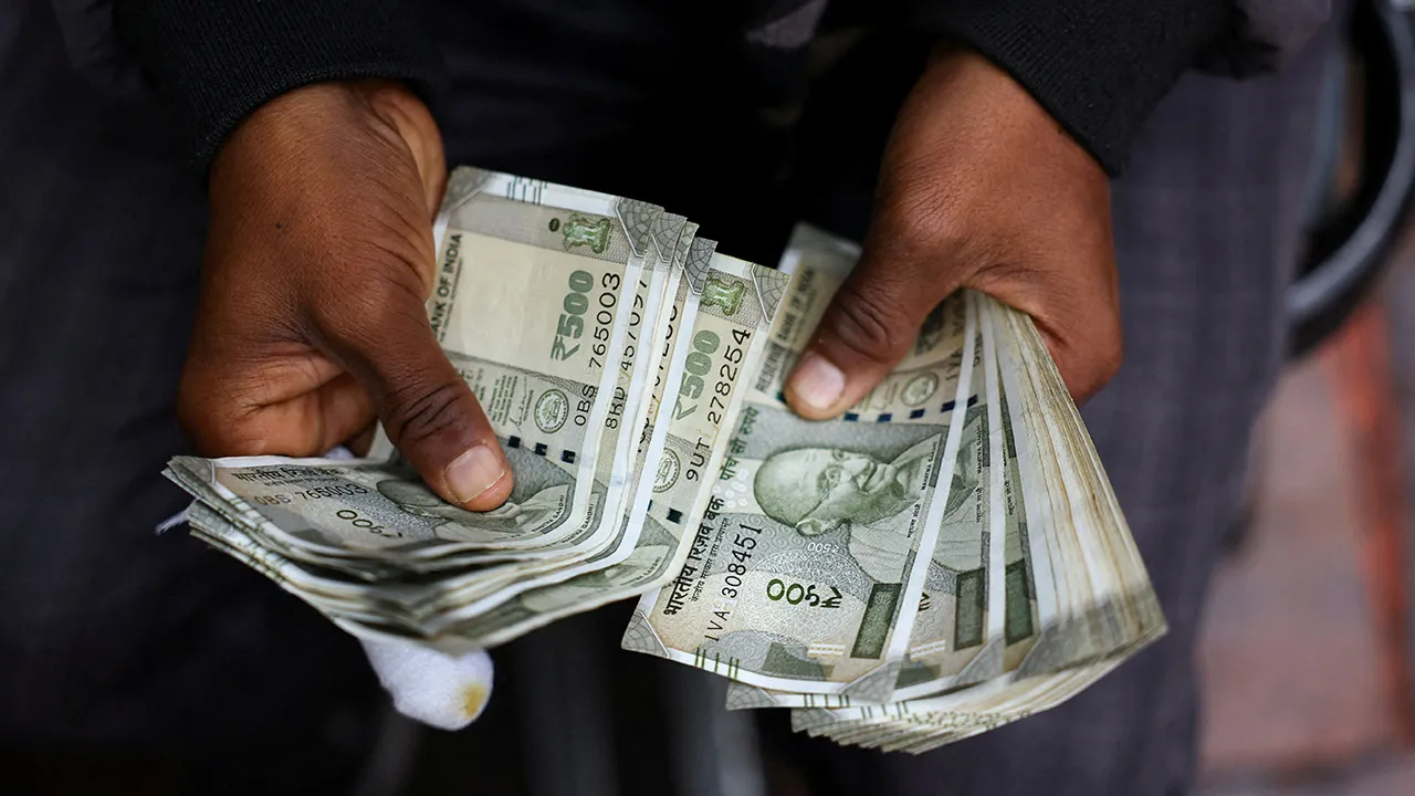 FILE PHOTO: A man counts Indian currency notes at a roadside currency exchange stall in the old quarters of Delhi, India, February 2, 2026. REUTERS/Anushree Fadnavis/File Photo