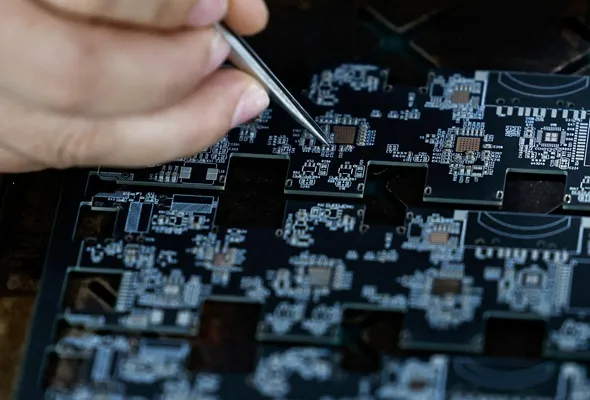  An employee uses a pair of tweezers to adjust microchips and electronic components on a printed circuit board at a factory, which is in partnership with Agilian Technology, in Dongguan, Guangdong province, China March 16, 2026. REUTERS/Tingshu Wang/File Photo