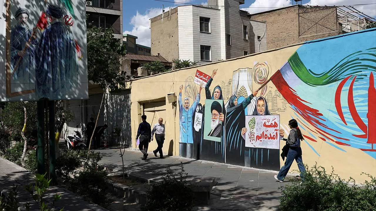 People walk on a street near a mural featuring an image of the late Supreme Leader of Iran, Ayatollah Ali Khamenei, in Tehran, Iran, May 18, 2026. Majid Asgaripour/WANA (West Asia News Agency) via REUTERS ATTENTION EDITORS - THIS PICTURE WAS PROVIDED BY A THIRD PARTY TPX IMAGES OF THE DAY