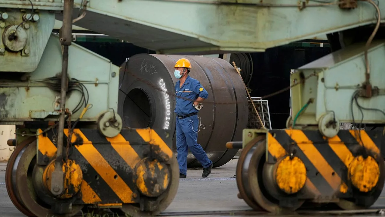 An employee walks past rolled steel at a port during a government-organised media tour to Baoshan Iron & Steel Co., Ltd. (Baosteel), a subsidiary of China Baowu Steel Group, in Shanghai, China September 16, 2022. REUTERS/Aly Song/File Photo