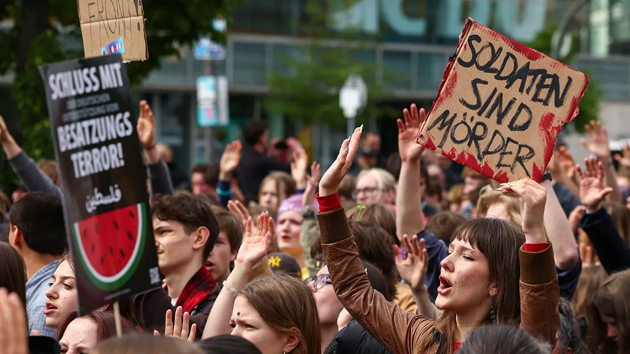 A demonstrator holds a placard during a protest against the potential return of military conscription, on the day of the 81st anniversary of the end of World War II, also known as Victory in Europe (VE) Day, outside of the Christian Democratic Union (CDU) headquaters, in Berlin, Germany, May 8, 2026. Military service in the Bundeswehr currently remains voluntary but the new law on modernising military service introduces an obligation for male German citizens turning 18 to provide information on their physic
