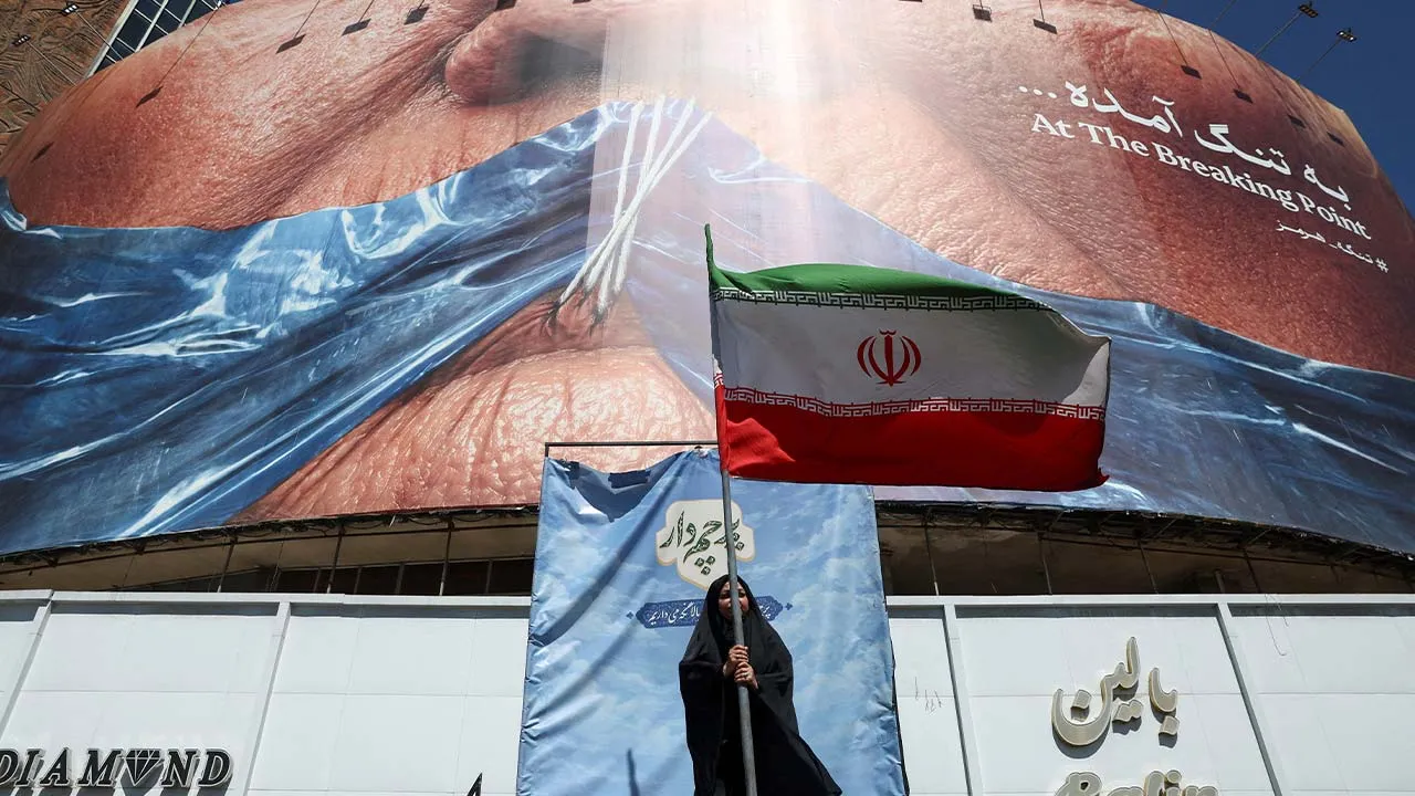 A woman holds an Iranian flag near an anti-U.S. billboard depicting U.S. President Donald Trump and the Strait of Hormuz, in Tehran, Iran, May 25, 2026. Majid Asgaripour/WANA (West Asia News Agency) via REUTERS ATTENTION EDITORS - THIS PICTURE WAS PROVIDED BY A THIRD PARTY