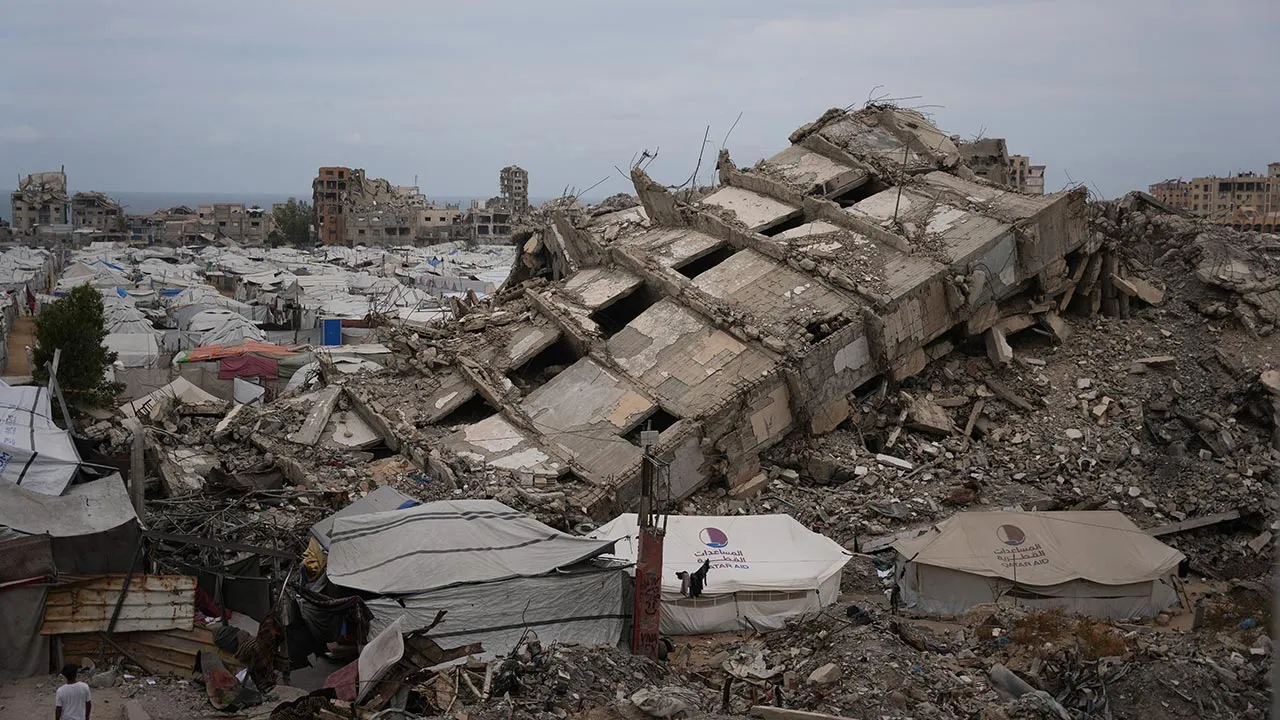 A tent camp for displaced Palestinians stretches among the ruins of buildings destroyed during the Israel Hamas war, in Gaza City, Friday, May 15, 2026. (AP Photo/Abdel Kareem Hana)