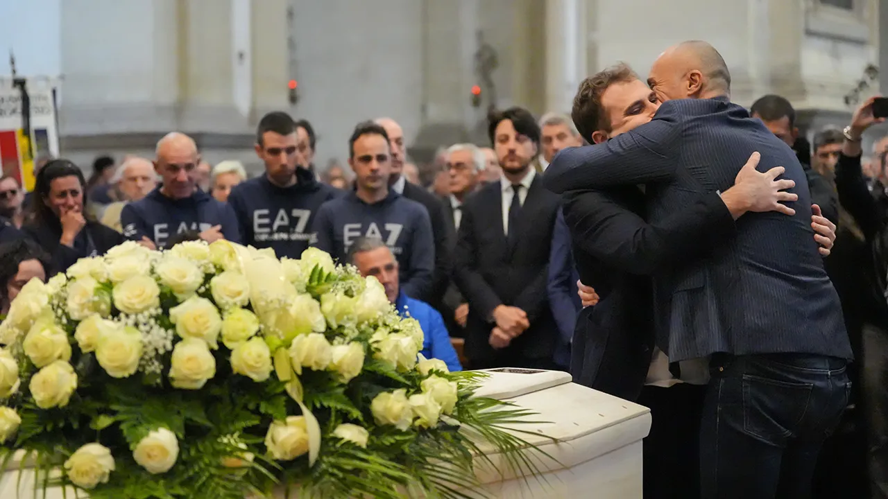 Niccolò Zanardi, son of Alex Zanardi, Italian auto racing champion-turned-Paralympic gold medalist, hugs family friend Federico Zanelli, right, mourn over the coffin during Alex Zanardi's funeral ceremony inside the Basilica of Santa Giustina, Padua, Italy, Tuesday, May 5, 2026. (Claudio Furlan/LaPresse via AP)