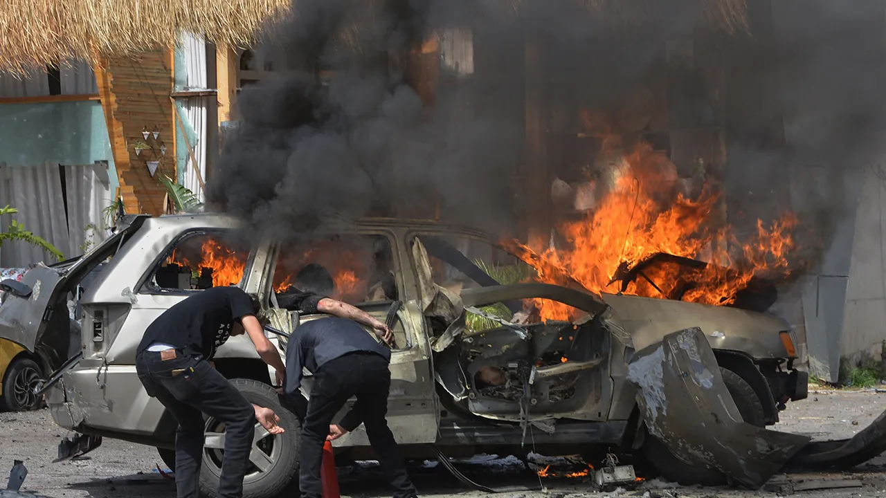 A person is seen inside a burning vehicle as men attempt to put out the fire after an Israeli airstrike hit a car in the coastal town of Barja, south of Beirut, Lebanon, Wednesday, May 13, 2026. (AP Photo/Mustafa Jamalddine)