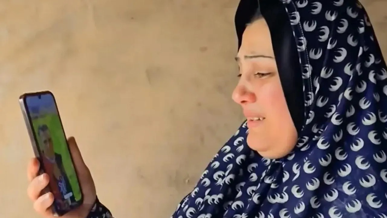 Gaza mother Maha Abu Shaar holds her phone displaying a photo of her son Eid as she cries with joy and sadness after discovering he is alive but in an Israeli prison [Screengrab/Al Jazeera]