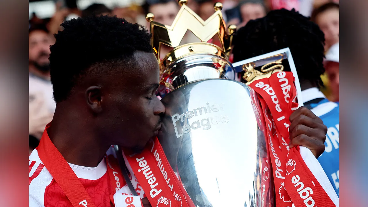 Soccer Football - Premier League - Crystal Palace v Arsenal - Selhurst Park, London, Britain - May 24, 2026 Arsenal's Bukayo Saka celebrates with the trophy after winning the Premier League REUTERS/Hannah Mckay EDITORIAL USE ONLY. NO USE WITH UNAUTHORIZED AUDIO, VIDEO, DATA, FIXTURE LISTS, CLUB/LEAGUE LOGOS OR 'LIVE' SERVICES. ONLINE IN-MATCH USE LIMITED TO 120 IMAGES, NO VIDEO EMULATION. NO USE IN BETTING, GAMES OR SINGLE CLUB/LEAGUE/PLAYER PUBLICATIONS. PLEASE CONTACT YOUR ACCOUNT REPRESENTATIVE FOR FURTH