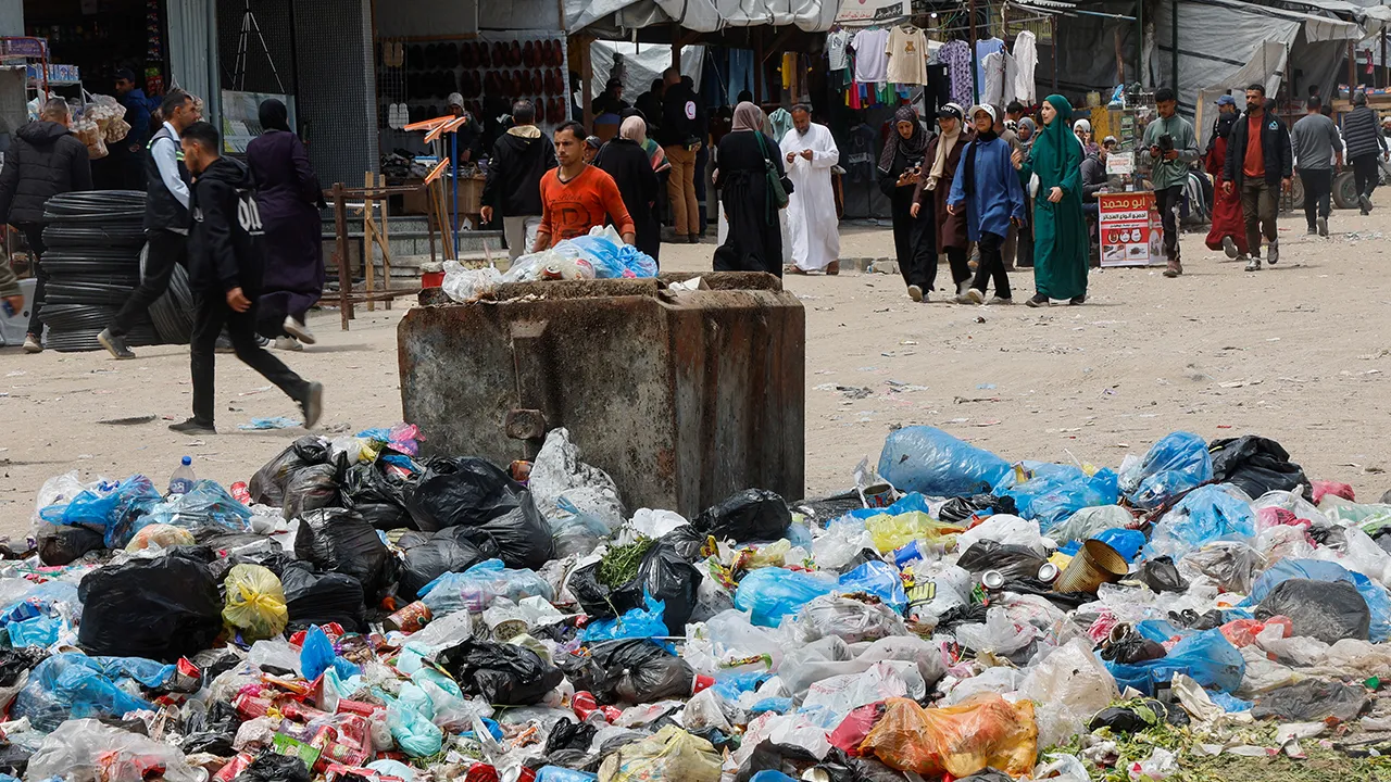 Palestinians walk past piles of garbage and waste near tents for displaced people, amid the spread of rodents, in Khan Younis in the southern Gaza Strip, April 27, 2026. REUTERS/Haseeb Alwazeer