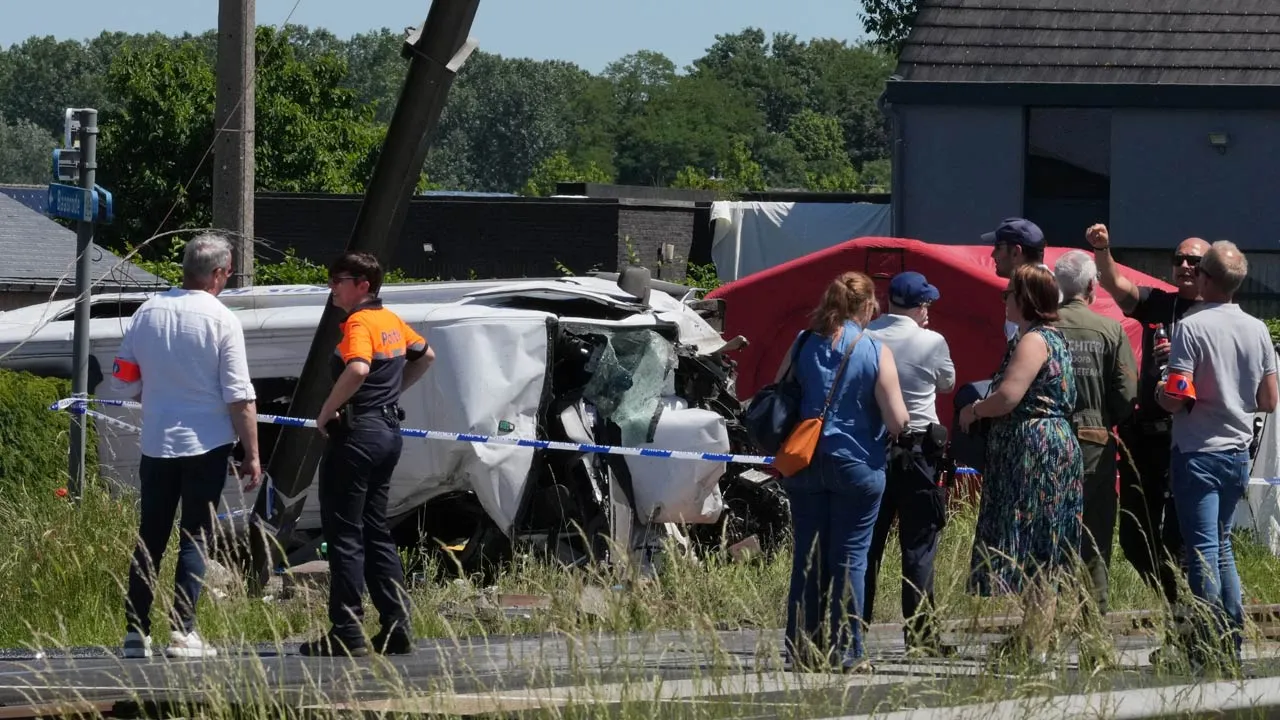Police and residents gather around a level crossing where a train collided with a van in Buggenhout, Belgium, Tuesday, May 26, 2026. (AP Photo/Marius Burgelman)