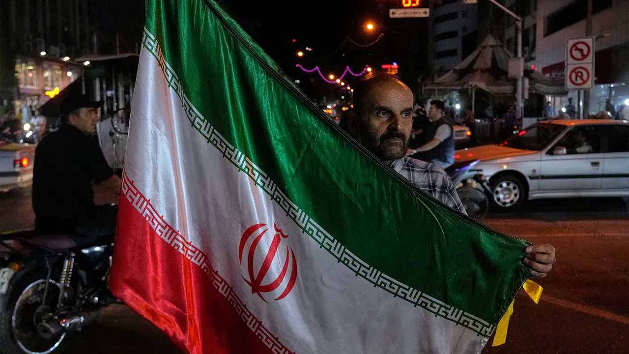 A man holds an Iranian flag for a pro-government campaign in downtown Tehran, Iran, Friday, May 8, 2026. (AP Photo/Vahid Salemi)