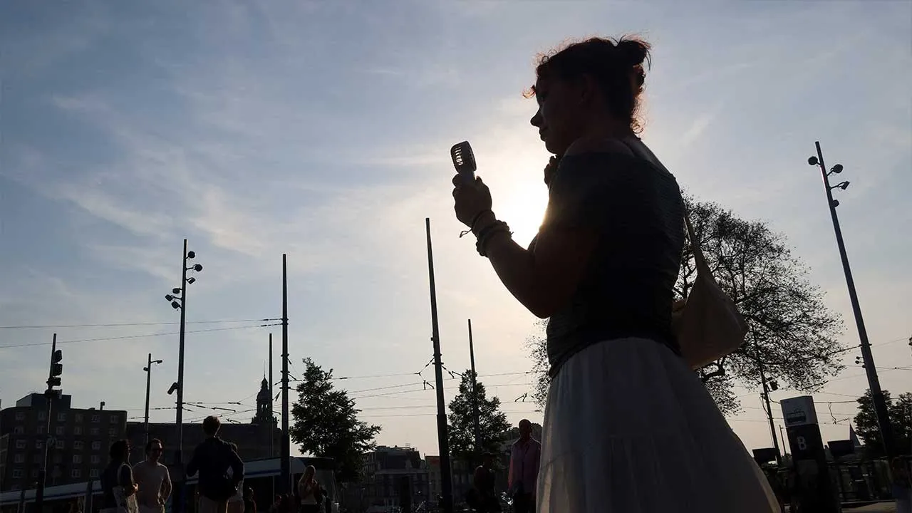 A woman is silhouetted as she holds a portable fan during a heatwave hitting the country, while a code red alert is issued, in Amsterdam, the Netherlands, June 26, 2026. REUTERS/Nicolas Economou