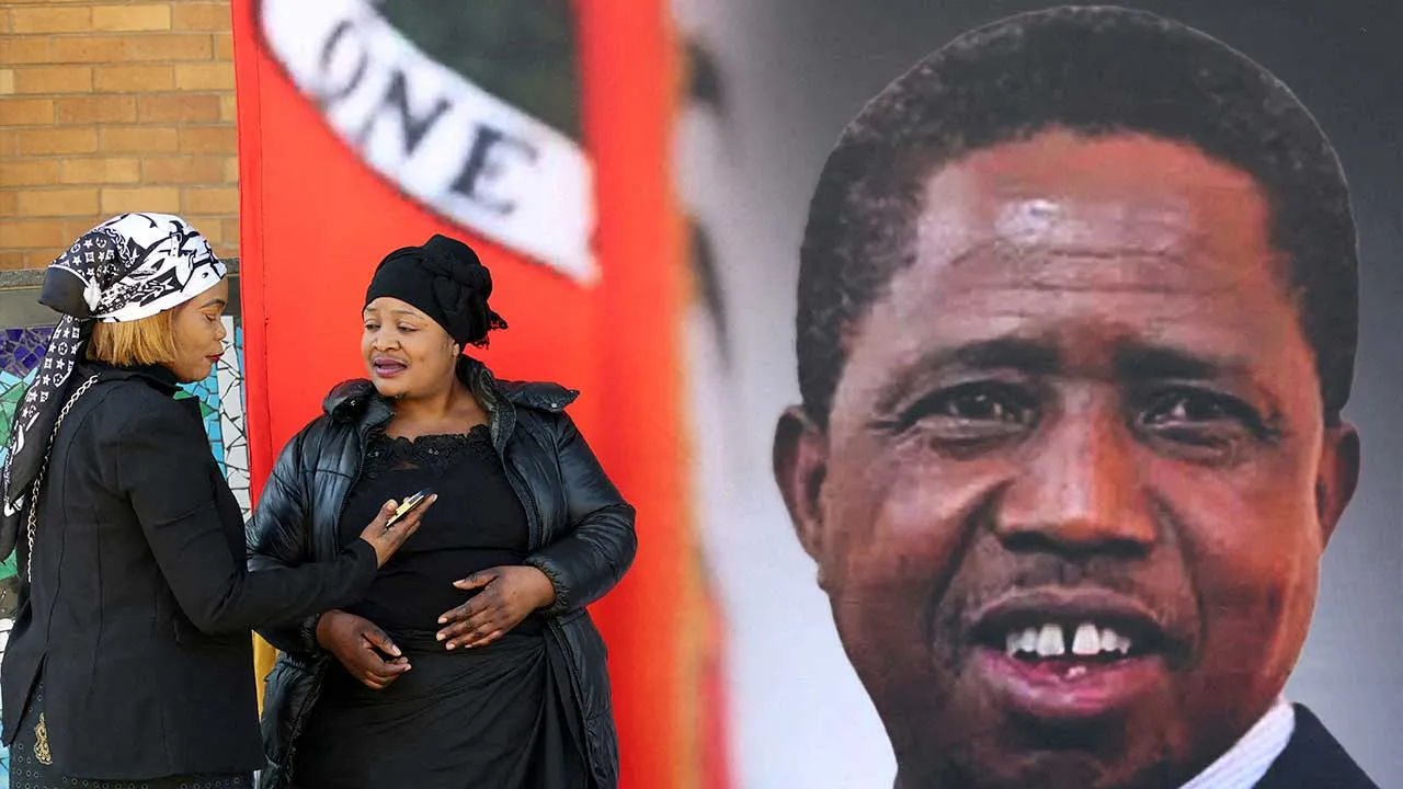 FILE PHOTO: Mourners gather in front of a banner ahead of the funeral of Zambia's former President Edgar Lungu, who died on June 5 while receiving treatment for an undisclosed illness in a South African hospital, before a church service at the Cathedral of Christ the King, and a private burial, in Hillbrow, Johannesburg June 25, 2025. REUTERS/Siphiwe Sibeko/File Photo