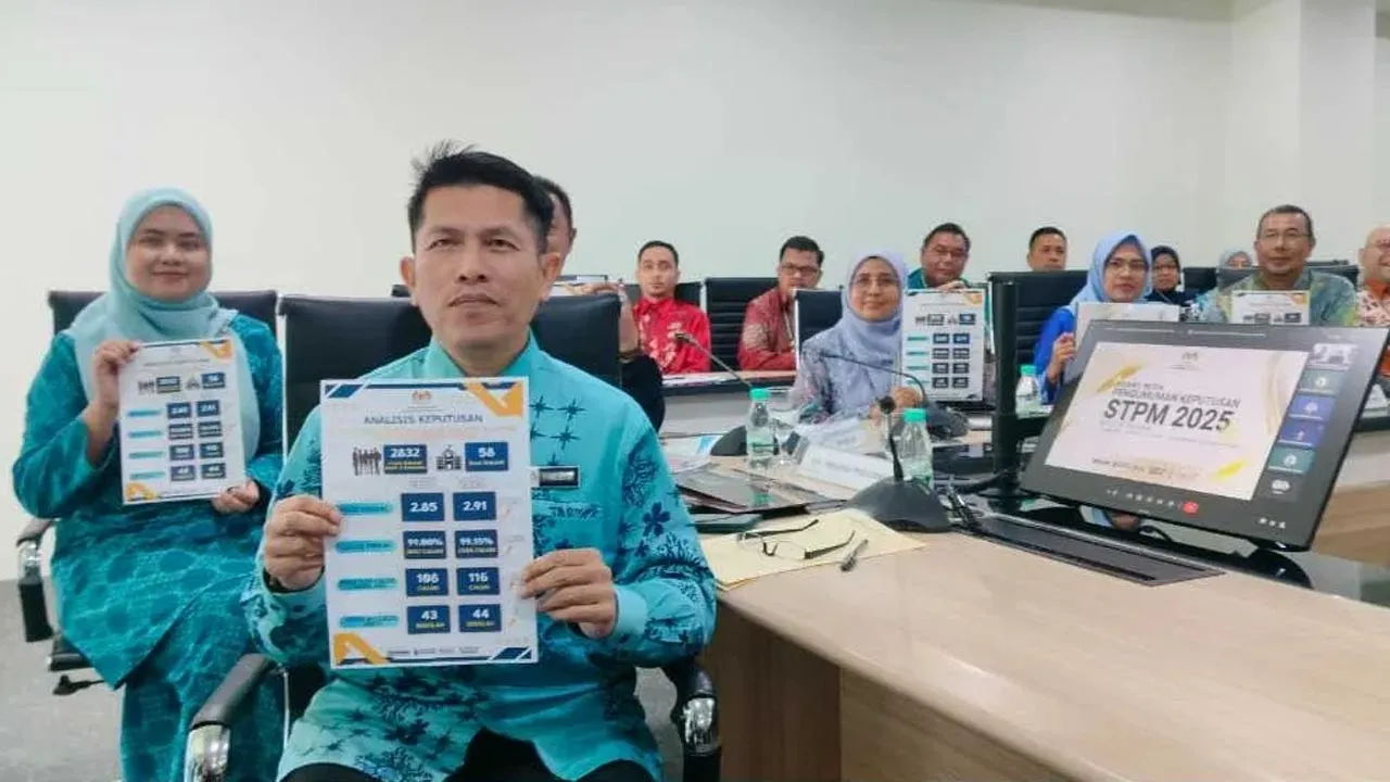 Ahmad Faidzul (hadapan) menunjukkan info grafik prestasi keputusan STPM negeri Perak di JPN Perak pada Khamis. -- SINAR HARIAN