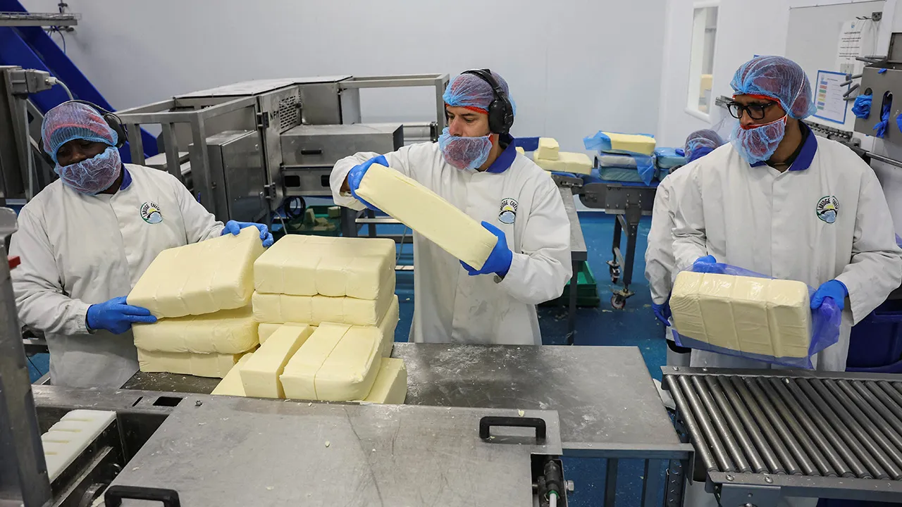 Workers transfer blocks of cheese along a production line at the Bridge Cheese factory in Telford, Britain, June 10, 2026. REUTERS/Temilade Adelaja