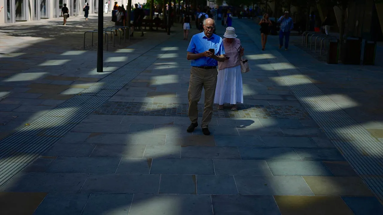 People walk in the shade in London, as a heatwave is forecast to develop in the coming days, Friday, June 19, 2026. (AP Photo/Kin Cheung)