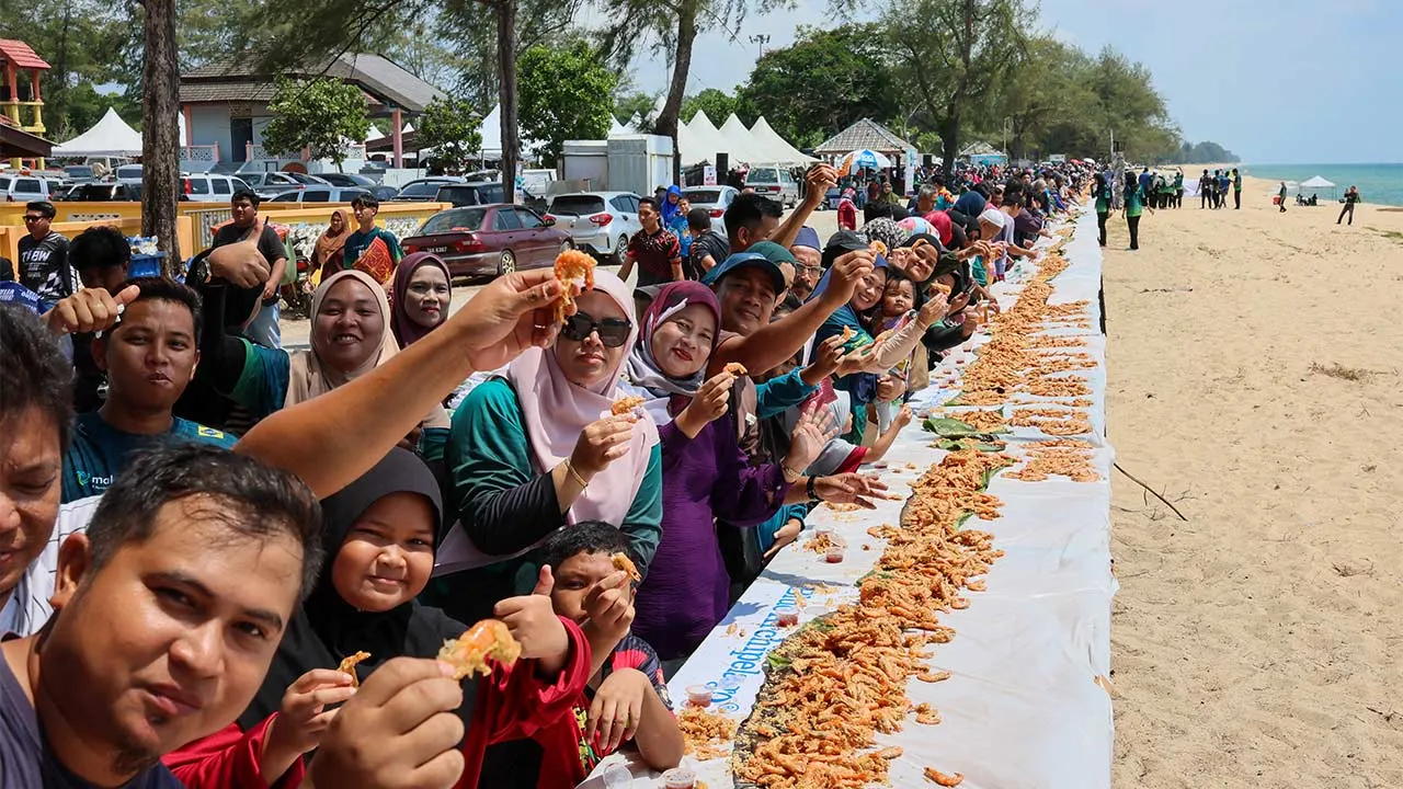BANDAR PERMAISURI, 27 Jun -- Orang ramai berpeluang menikmati hidangan Udang Celup Tepung Terpanjang sempena Karnival Pekan Budaya Daerah Setiu yang berjaya mencipta rekod Malaysia Book of Records (MBOR) di Laman Seri Rhu Sepuluh, hari ini.  Hidangan ikonik itu dijayakan menerusi gotong-royong 21 pengusaha kedai udang celup tepung terkenal dari sekitar Pantai Penarik dan Kampung Rhu Sepuluh yang menyusun hidangan di atas 547 buah meja.  Sebanyak satu tan metrik udang atau kira-kira 100,000 ekor digunakan ba