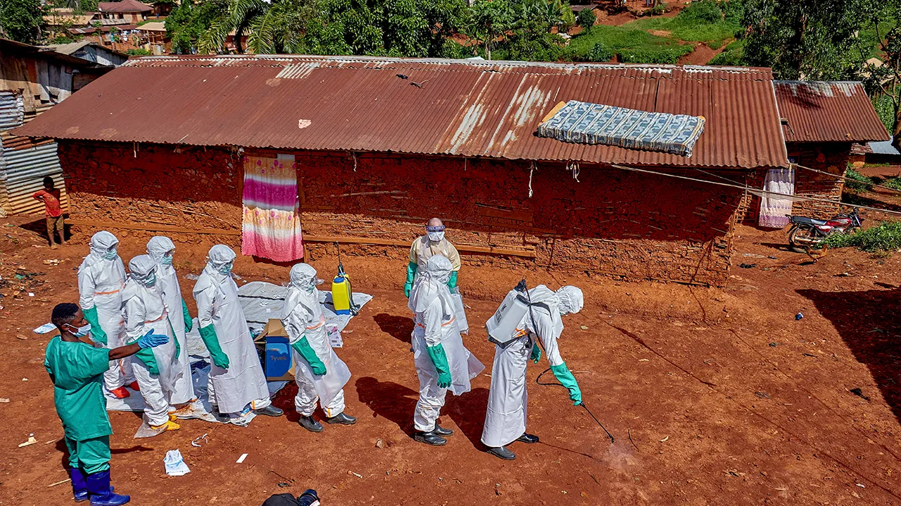 Red Cross workers wearing personal protective equipment walk in a formation as they disinfect the ground outside the house of an unidentified man who died of Ebola, before retrieving his body, as aid agencies intensify efforts to contain a new Ebola outbreak involving the Bundibugyo strain, in Quartier Shuni 1, a residential sector in Mongbwalu, Djugu Territory of Ituri province, Democratic Republic of Congo, May 24, 2026. REUTERS/Gradel Muyisa Mumbere