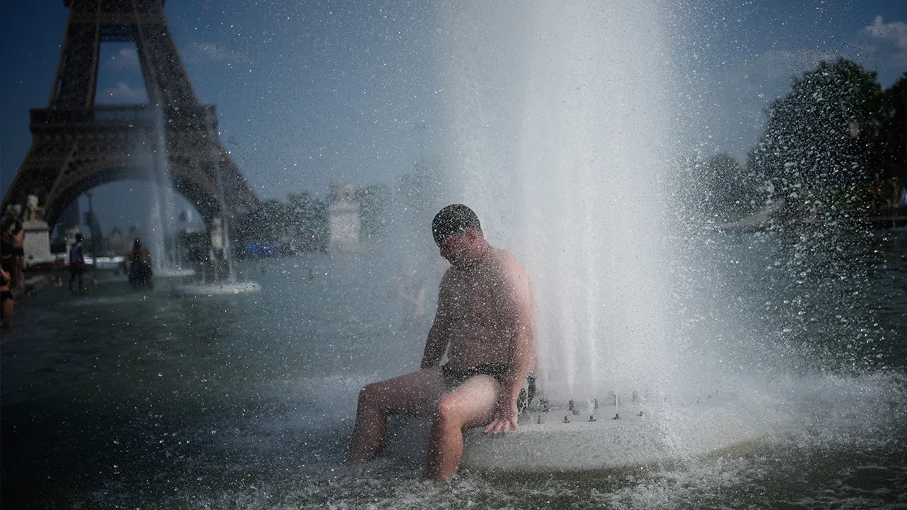 A person cools off at Trocadero fountain near the Eiffel Tower during a heat wave in Paris, on June 24, 2026. (AP Photo/Christophe Ena, File)