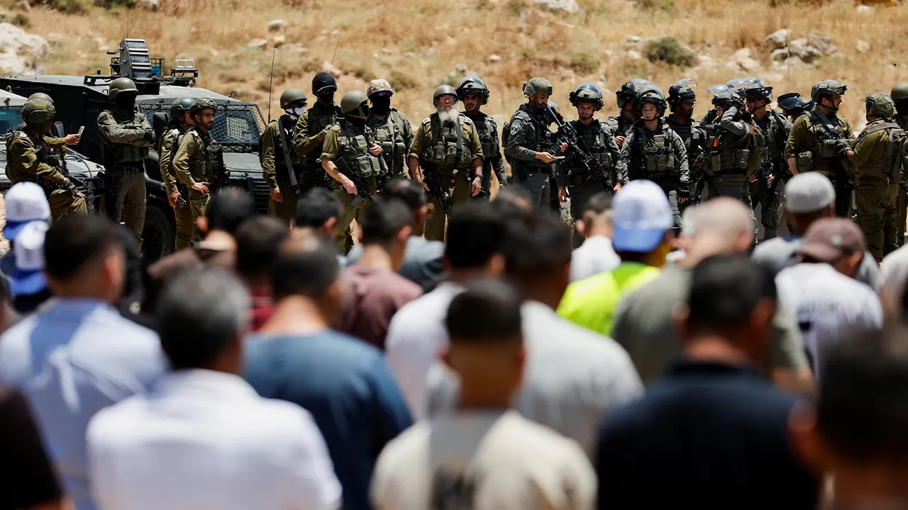 Israeli soldiers stand guard as Palestinians hold Friday prayers during a protest against settlements near Hebron in the Israeli-occupied West Bank, June 12,2026. REUTERS/Mussa Qawasma