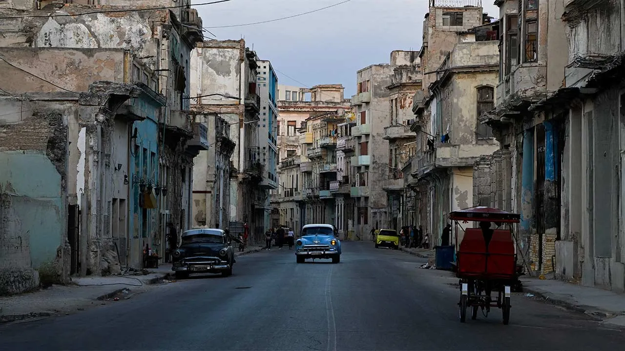 Vintage cars and a tricycle drive on a street downtown as Cuba's state-run economy has descended into a full-blown crisis after the administration of U.S. President Donald Trump hardened sanctions and cut off the Caribbean nation's oil supply, in Havana, Cuba, February 21, 2026. REUTERS/Norlys Perez