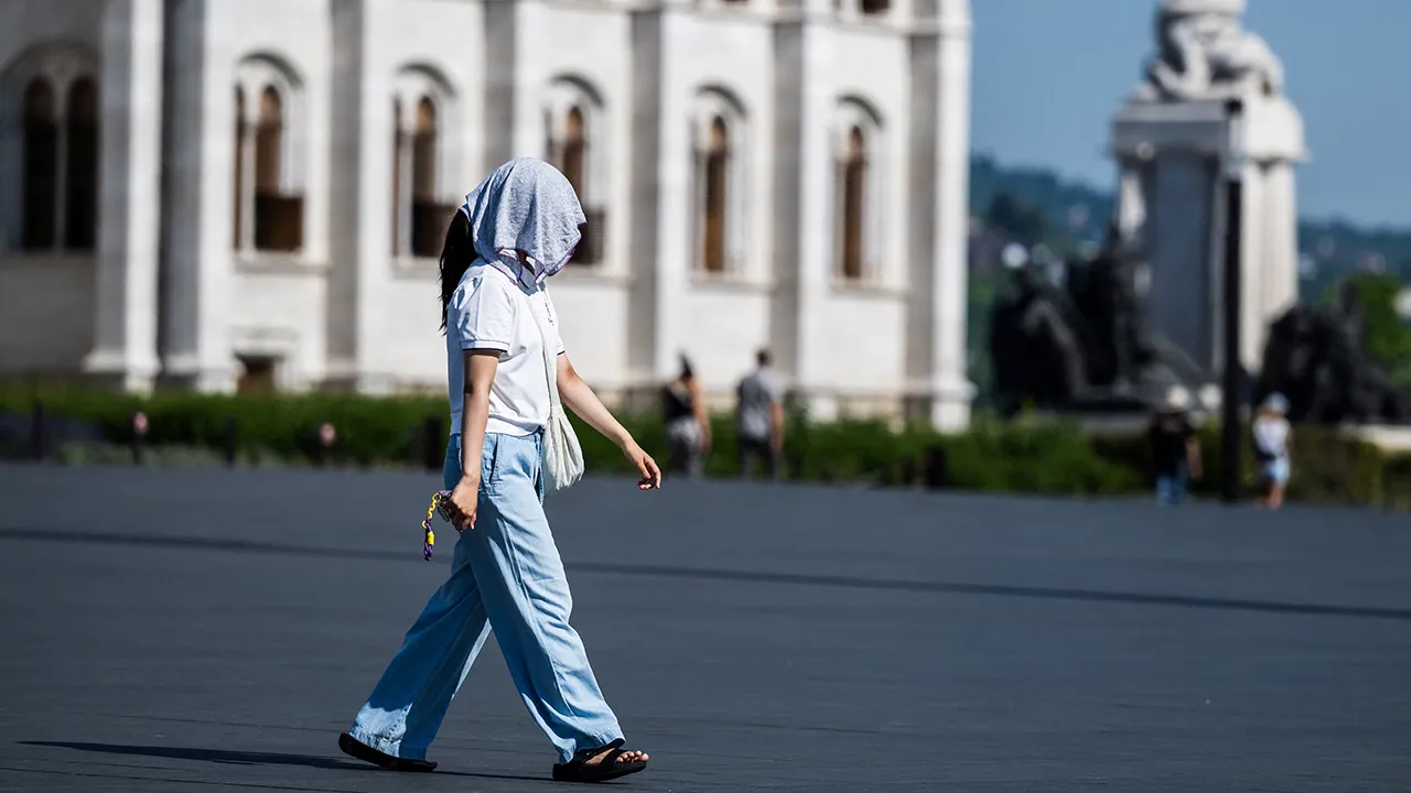 A woman shields herself from the sun with a towel over her head amid a heatwave in Budapest, Hungary, June 27, 2026. REUTERS/Marton Monus