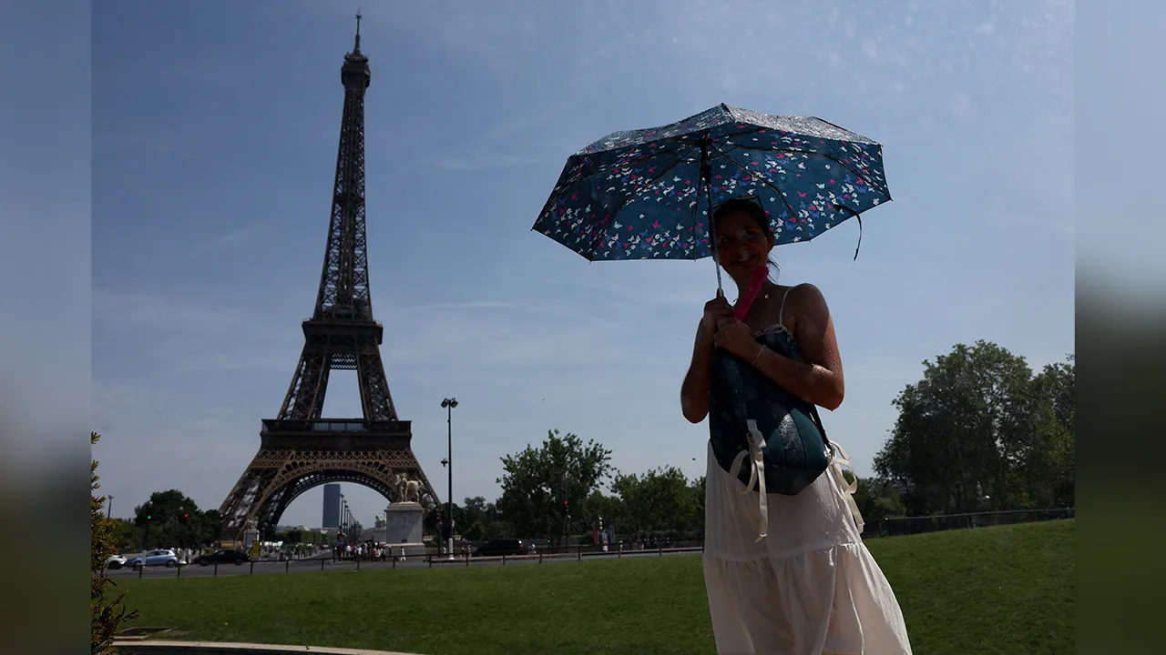 A person shelters under an umbrella by the Eiffel Tower during high temperatures amid a heatwave in Paris, France, June 27, 2026. REUTERS/Tom Nicholson