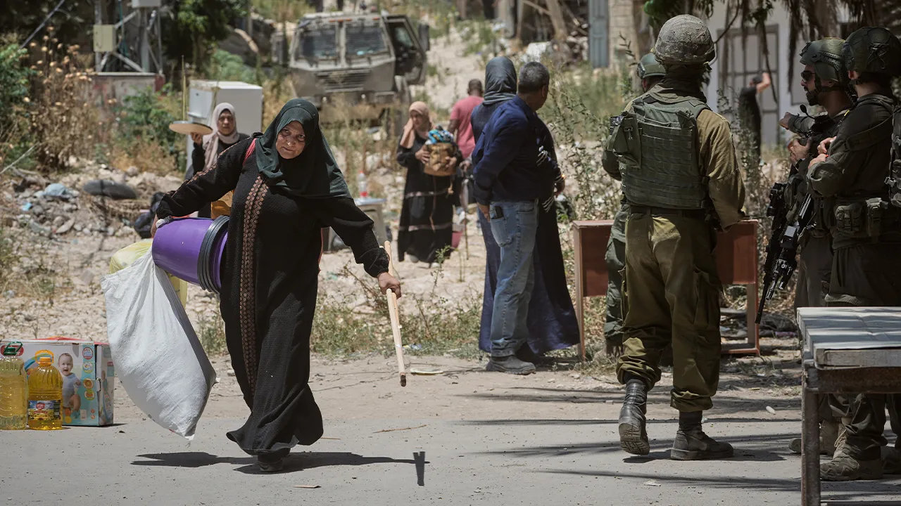Palestinians collect belongings from their evacuated homes in the Tulkarem refugee camp in the West Bank as Israeli soldiers stand nearby, Wednesday, June 17, 2026. (AP Photo/Majdi Mohammed)