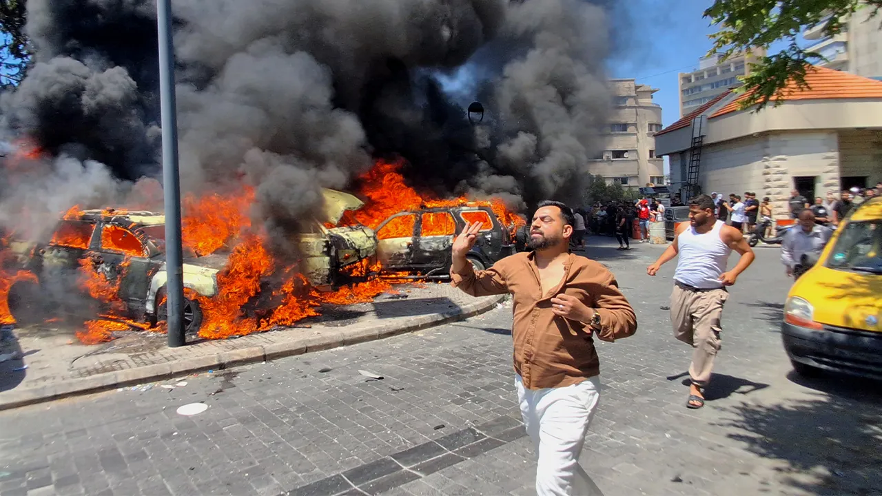 People run in front of burned cars that were attacked in an Israeli airstrike in the southern port city of Sidon, Lebanon, Wednesday, June 10, 2026. (AP Photo/Mohammed Zaatari)