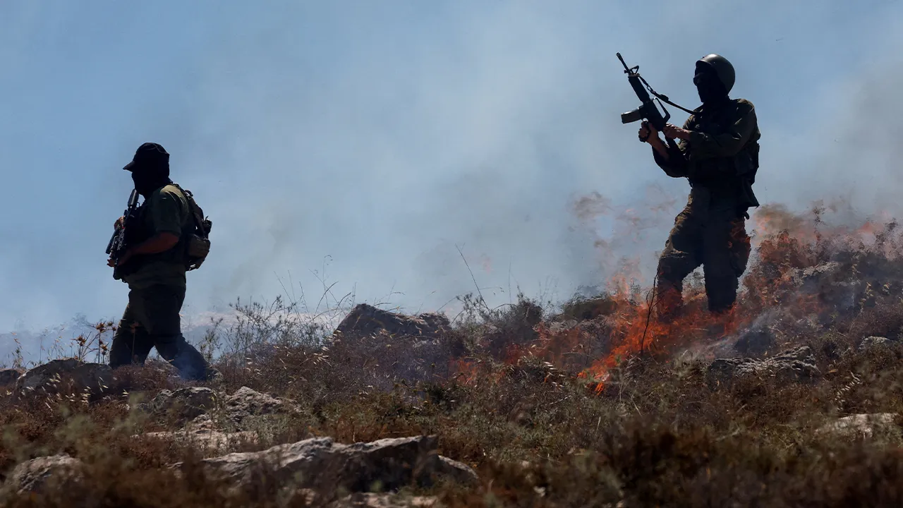Israeli troops walk amid smoke rising from a fire started by crowd control grenades, during a protest against a settlement near Hebron in the Israeli-occupied West Bank, June 9, 2026. REUTERS/Mussa Qawasma