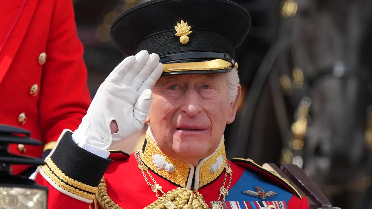Britain's King Charles III salutes as he rides with Queen Camilla in a open top carriage during Trooping The Colour, the King's annual birthday parade, in London, Saturday, June 13, 2026. (AP Photo/Kirsty Wigglesworth)