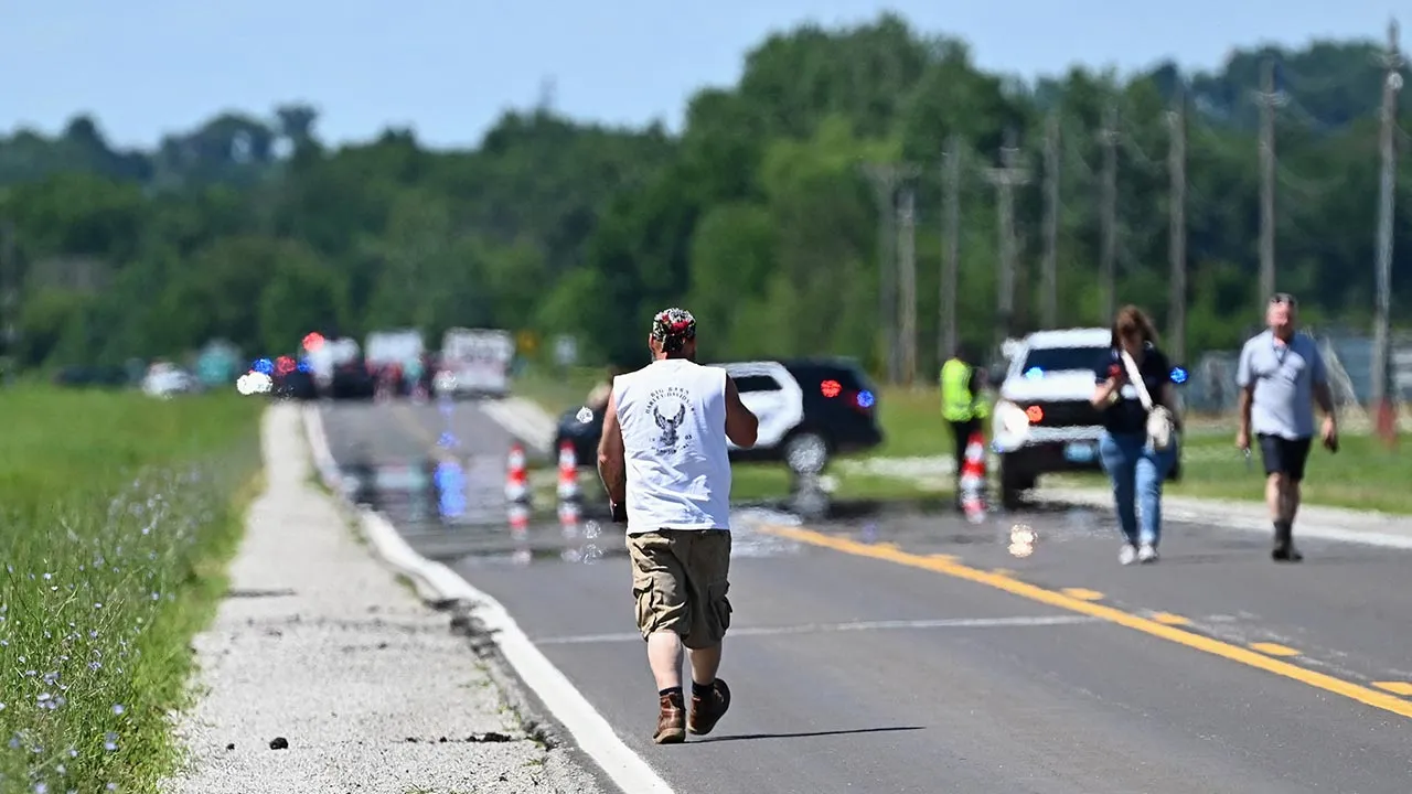 A man walks towards a Bates County Sheriff's Deputy's roadblock leading to Butler Memorial Airport after a plane carrying skydivers crashed in Butler, Missouri, U.S. June 14, 2026. REUTERS/Dave Kaup