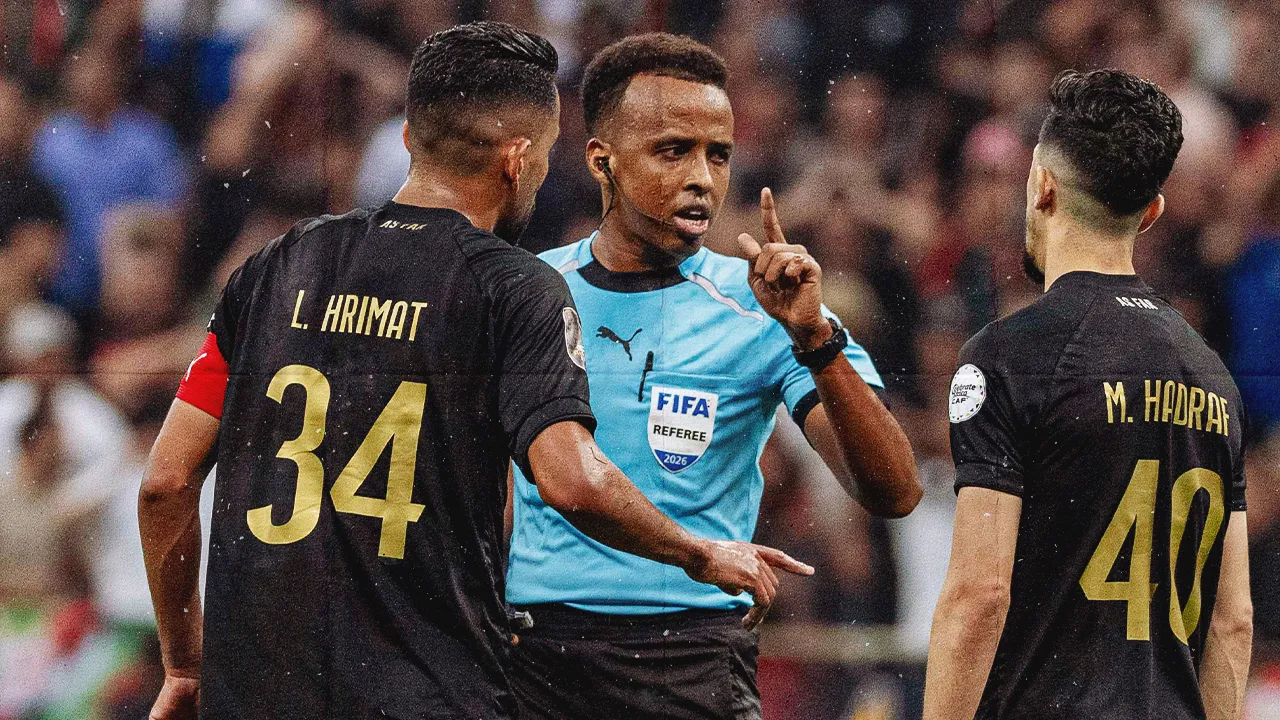 Referee Omar Artan, center, of Somalia, is confronted by players after calling a penalty kick during the CAF Champions League final soccer match between AS FAR Rabat and Mamelodi Sundowns, in Rabat, Morocco, Sunday, May 24, 2026. (AP Photo/Mosa'ab Elshamy)