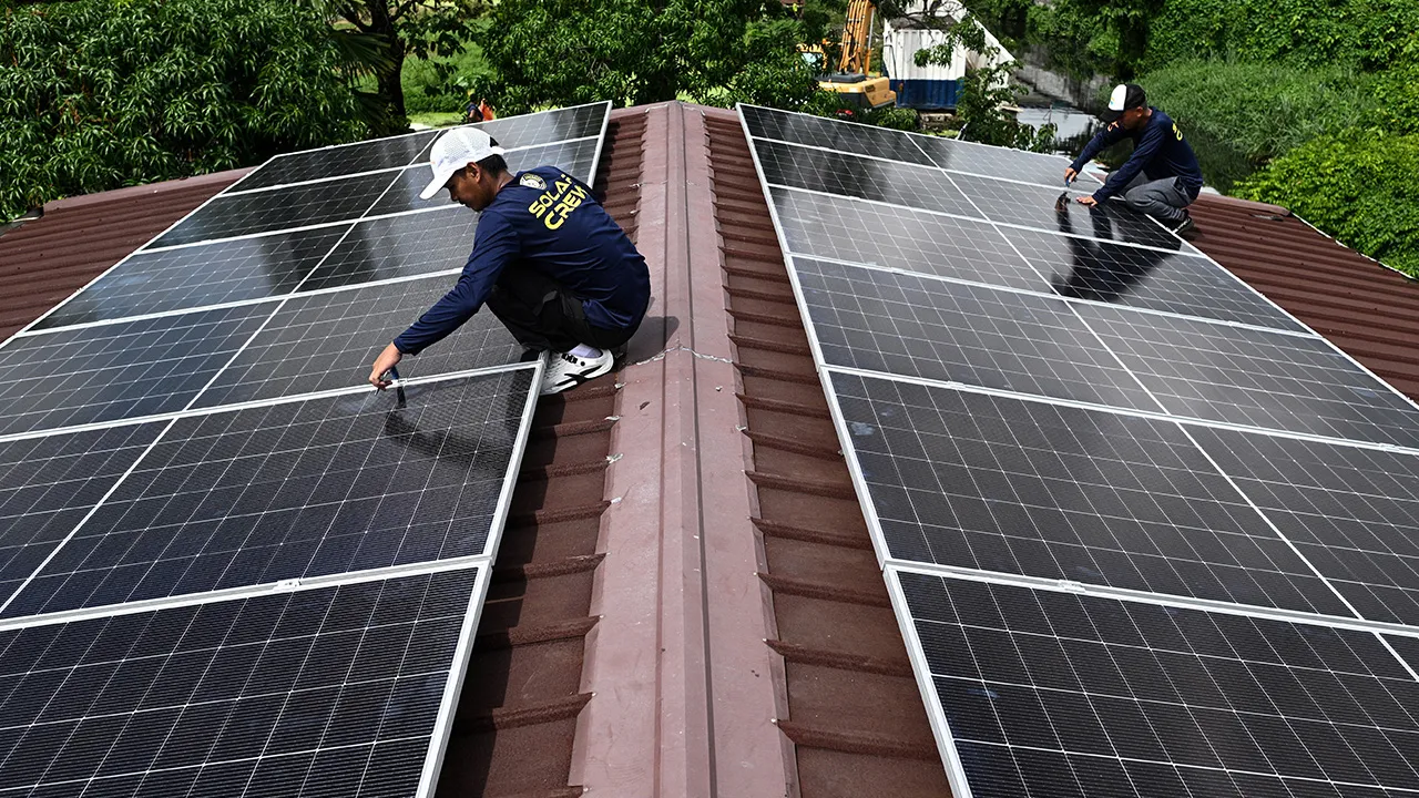 Workers install solar panels on the roof of a house in Kawit, Philippines, June 26, 2026. REUTERS/Noel Celis