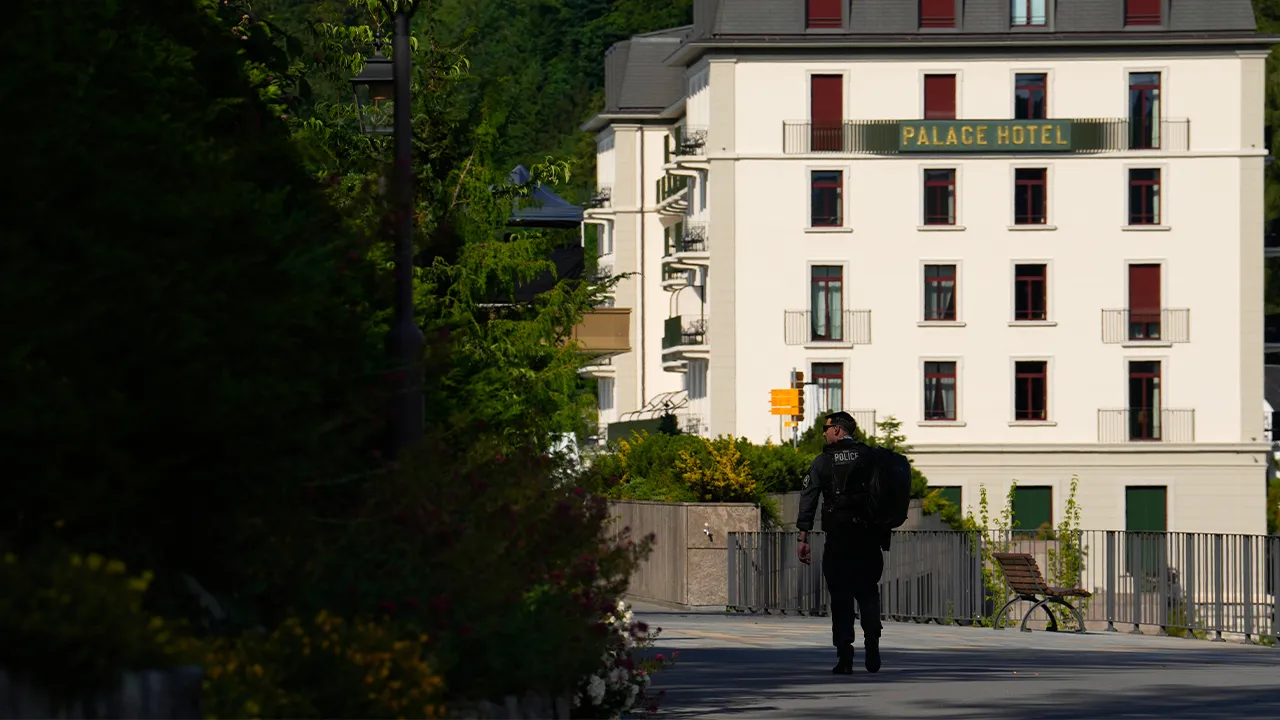 A member of the US Secret Service walks backdropped by the Palace Hotel where U.S. Iran negotiations take place at the Burgenstock Resort in Obbuergen, near Lucerne, in Switzerland, Sunday, June 21, 2026. (AP Photo/Vadim Ghirda)