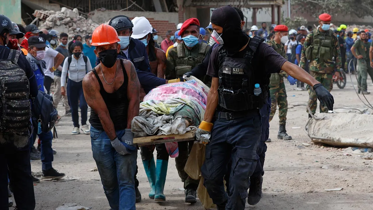 People carry a body recovered body during search and rescue operations days after earthquakes in La Guaira, Venezuela, Sunday, June 28, 2026. (AP Photo/Pedro Mattey)