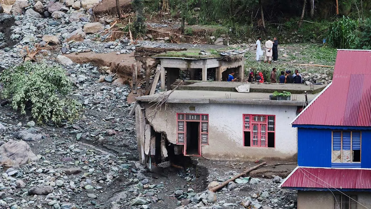 People stand near a house damaged due to a flash flood, in Poonch, Indian Kashmir, July 19, 2026. REUTERS/Stringer